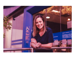 Mulher na frente de seu banco pensando em fazer uma portabilidade para outro banco